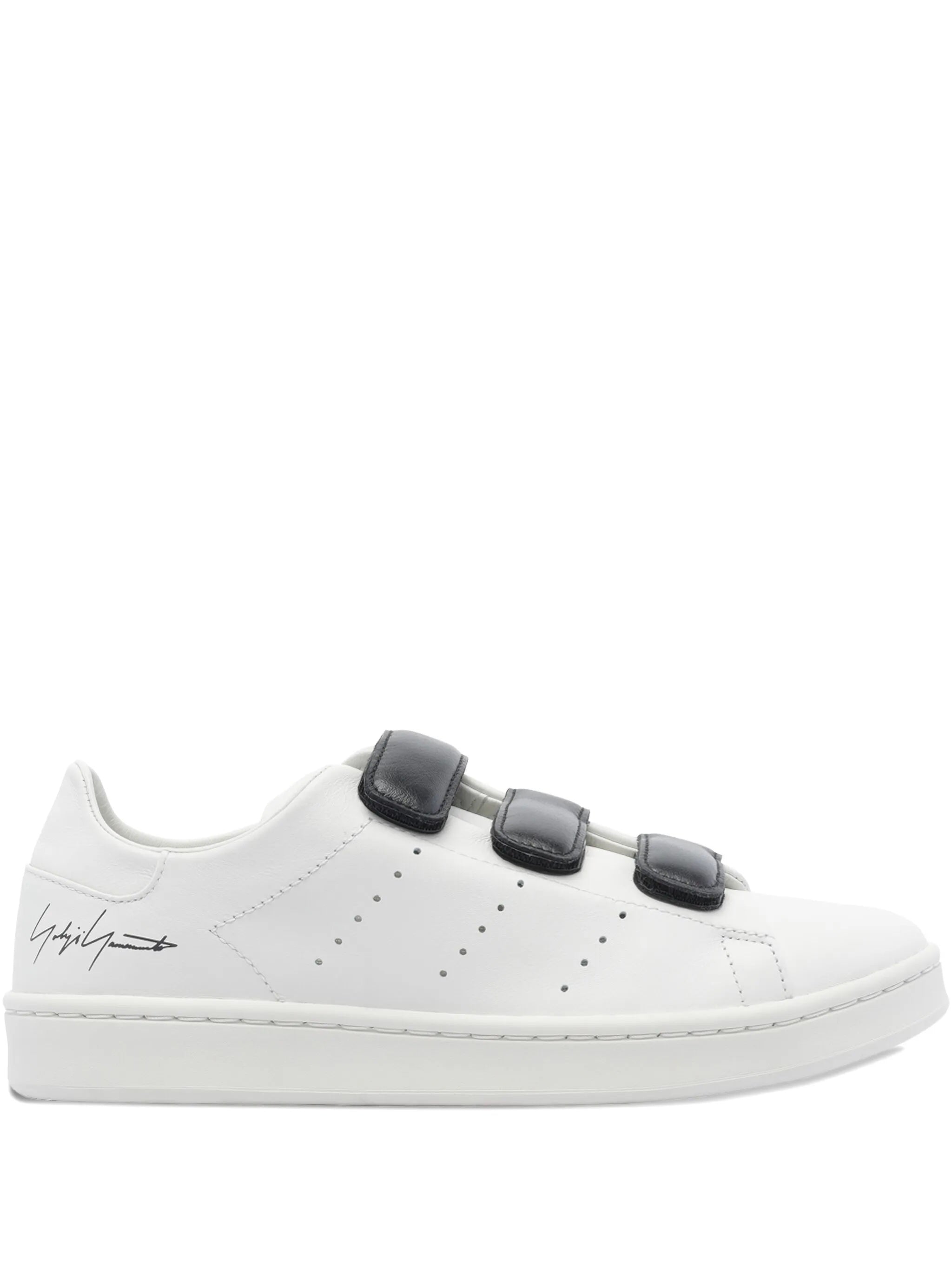 White sneaker with black velcro straps on a white background