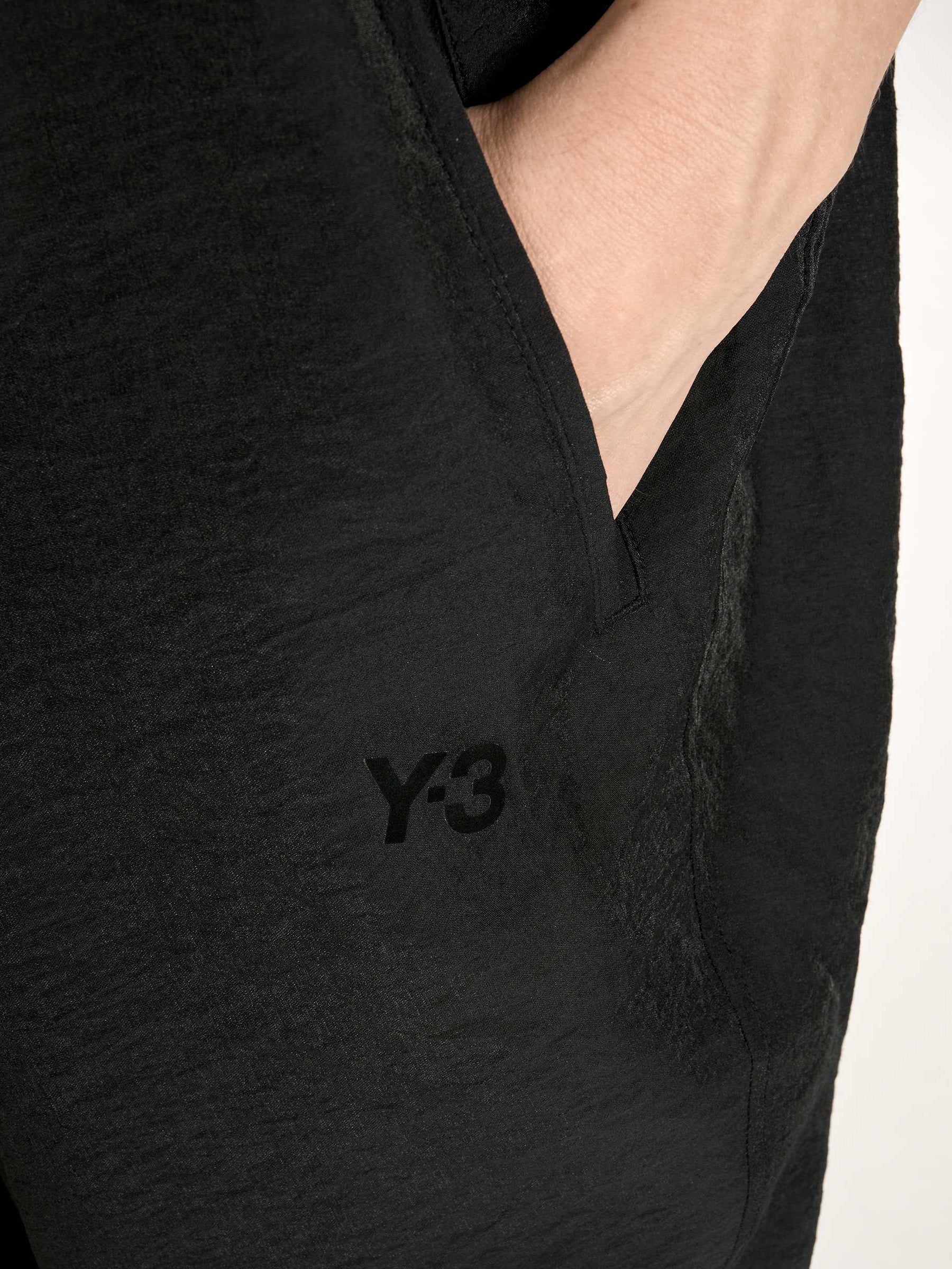 Close-up of the lower front of the Y-3 Women’s Utility Dress in Black on a model, emphasizing the fluid drape and hem detail.