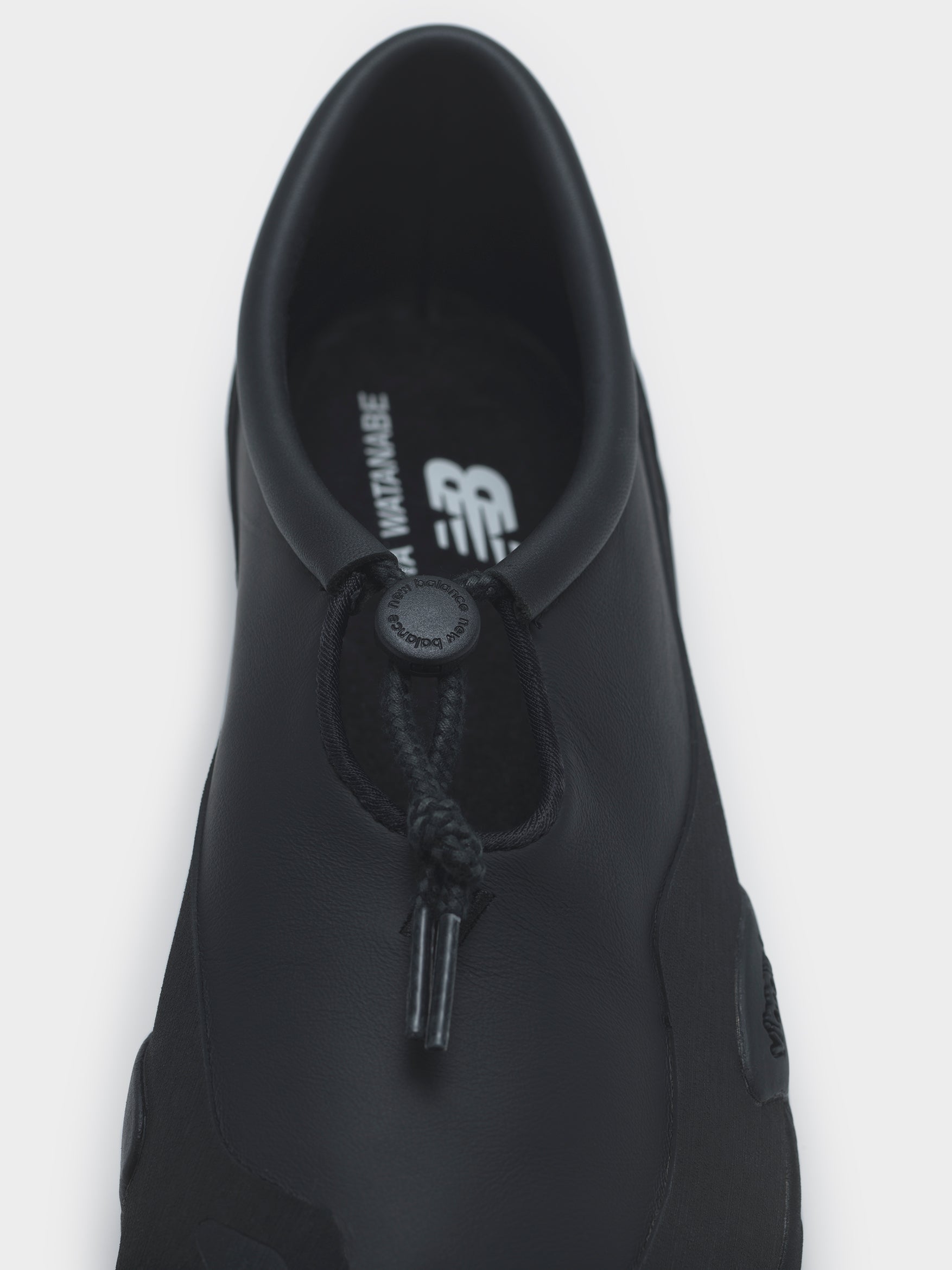 Junya Watanabe x New Balance MT10T Sneakers in Black — a sleek all-black low-profile sneaker with a minimalist silhouette, thin sole, and subtle lace detail, photographed from the top.